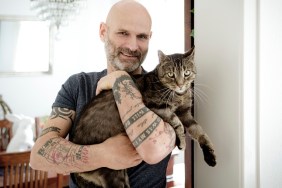 Tattooed man carrying his cat