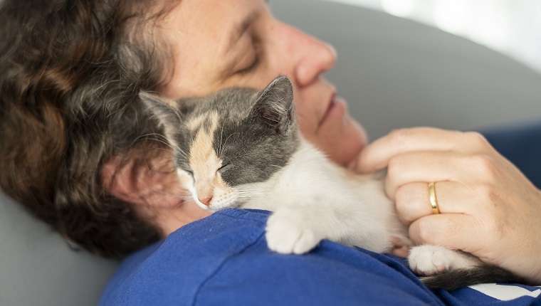 Close-up of a woman sleeping with her newly adopted kitten at home