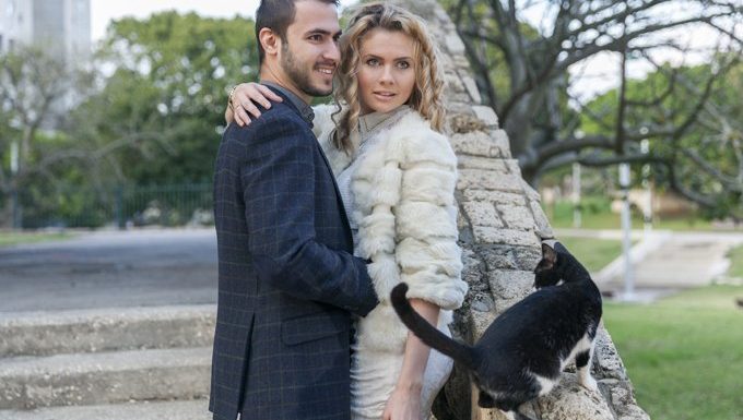 model couple stands in park with cat near by