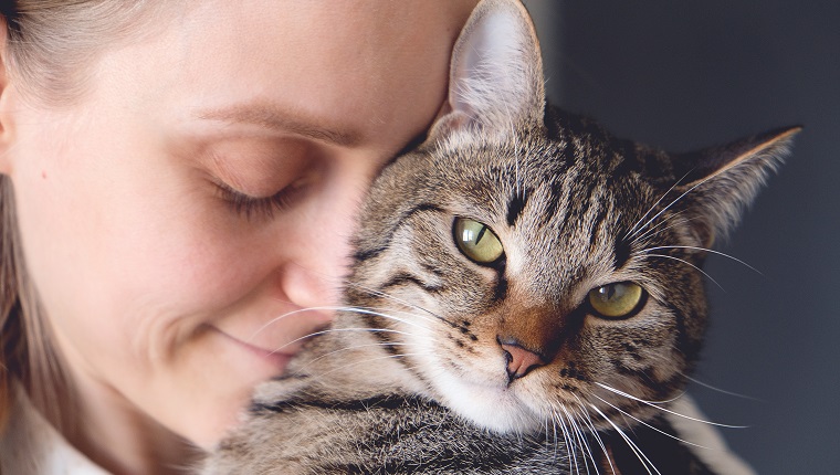 A woman Holds a Cat in her Arms and Hugs it.