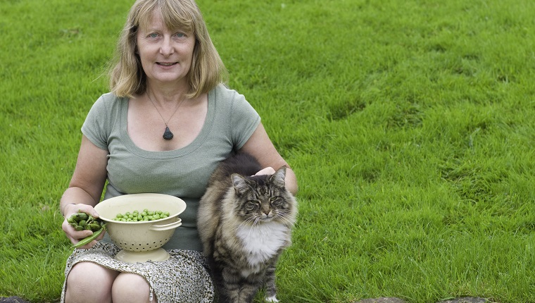 A contented gardener with her freshly grown peas and her contented cat.