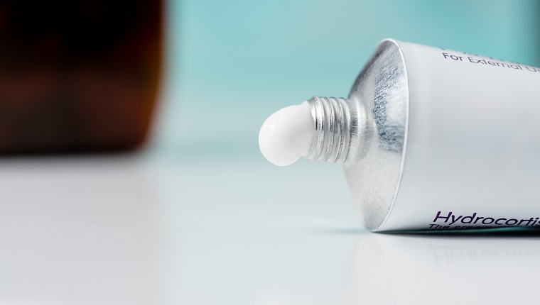 A tube of hydrocortisone cream on a domestic bathroom top with a blue background.