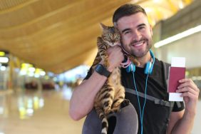 A man traveler hugging a therapy cat at an airport.